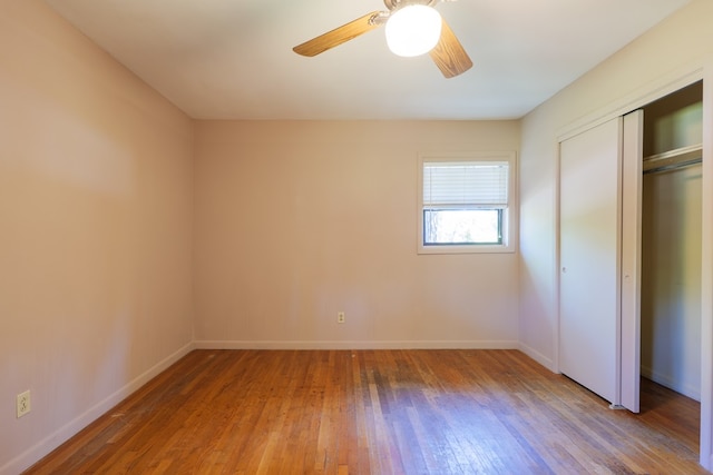 unfurnished bedroom featuring ceiling fan, a closet, and hardwood / wood-style flooring