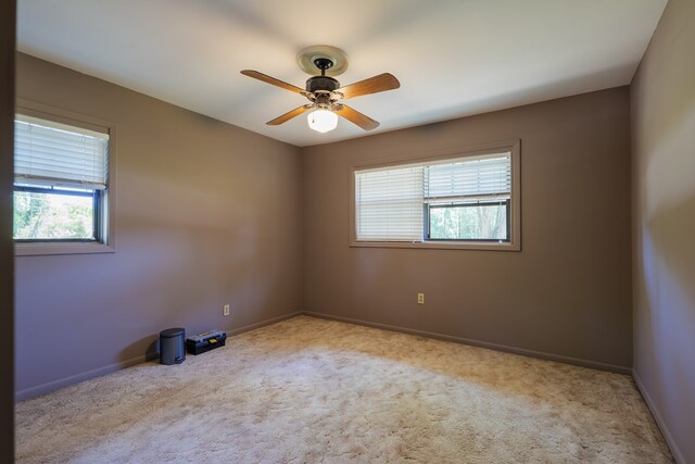 unfurnished room with light colored carpet, a wealth of natural light, and ceiling fan