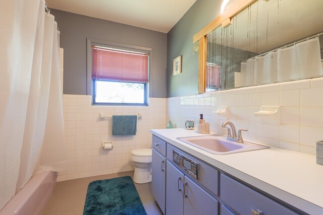 full bathroom featuring vanity, toilet, tile walls, and shower / tub combo