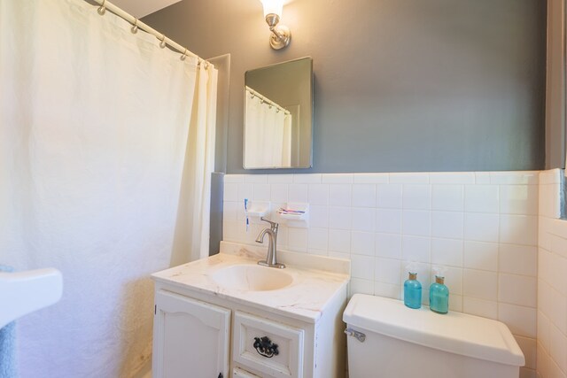 bathroom featuring vanity, toilet, and tile walls