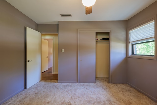 unfurnished bedroom featuring light colored carpet, a closet, and ceiling fan