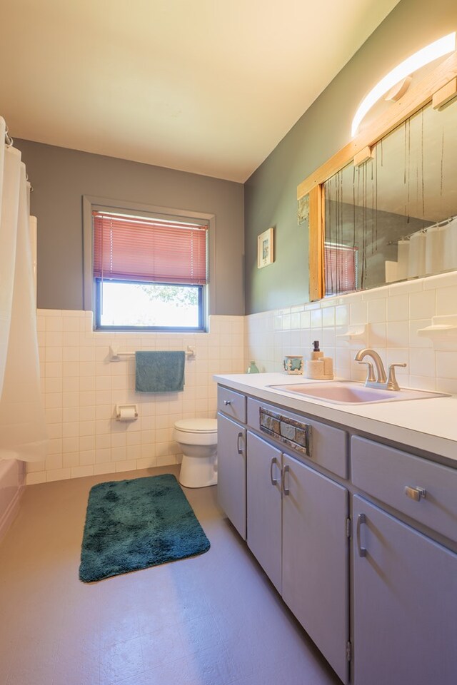 bathroom with vanity, toilet, and tile walls