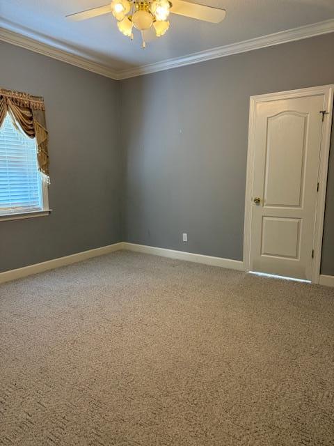 carpeted empty room featuring a ceiling fan, baseboards, and ornamental molding