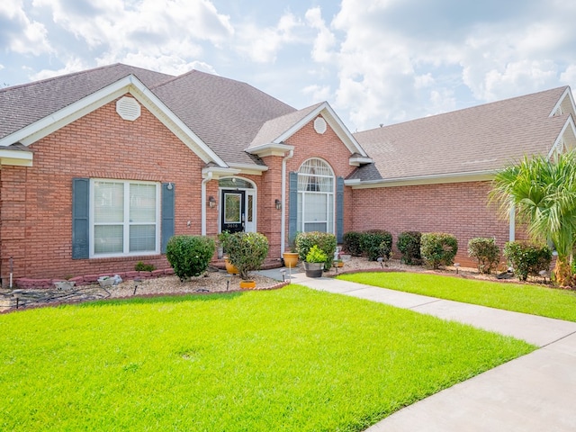 traditional home featuring brick siding, a front lawn, and a shingled roof