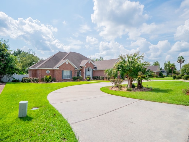 view of front facade with a front lawn, fence, brick siding, and curved driveway