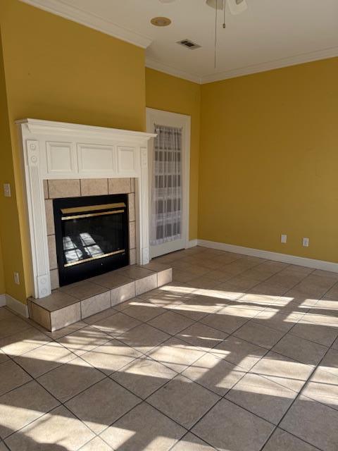 unfurnished living room featuring a tiled fireplace, visible vents, baseboards, and ornamental molding