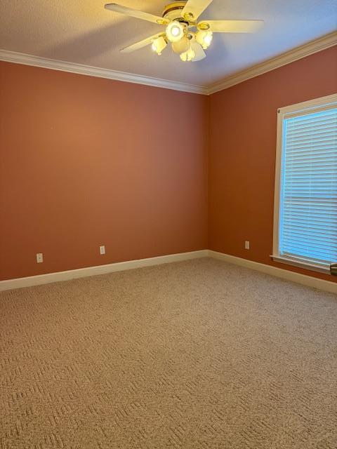 spare room with light carpet, baseboards, crown molding, and a ceiling fan