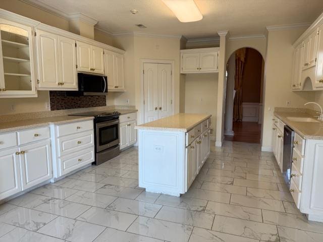 kitchen with marble finish floor, a sink, stainless steel range with electric cooktop, arched walkways, and white cabinets