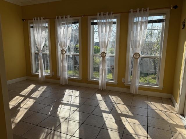 doorway featuring tile patterned floors, a healthy amount of sunlight, and baseboards