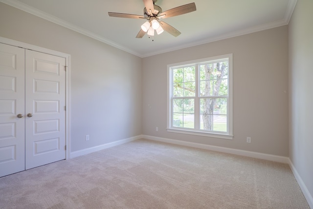 spare room featuring ceiling fan, ornamental molding, and light carpet