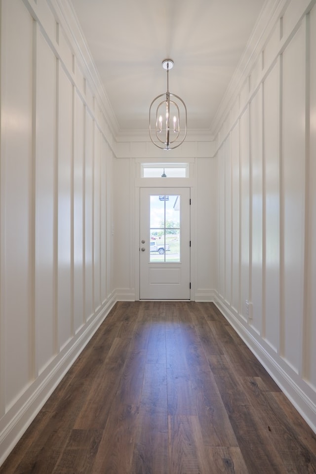 doorway featuring crown molding, dark wood-type flooring, and an inviting chandelier