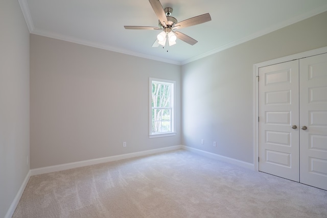 spare room with ceiling fan, light colored carpet, and ornamental molding