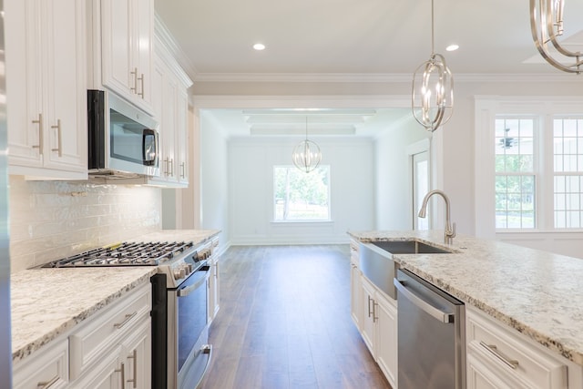 kitchen featuring sink, light hardwood / wood-style floors, decorative light fixtures, white cabinets, and appliances with stainless steel finishes