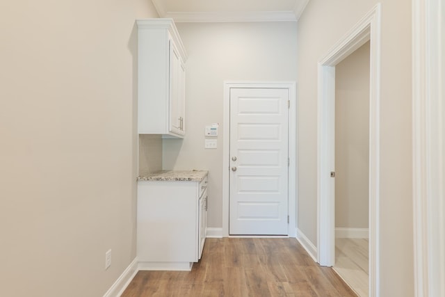 clothes washing area with light wood-type flooring and crown molding