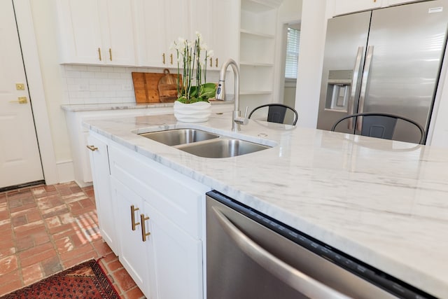 200 E College St, Valdosta, GA 31602 - kitchen featuring decorative backsplash, a sink, white cabinets, brick floor, and stainless steel appliances