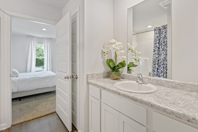 bathroom with recessed lighting, a shower with shower curtain, wood finished floors, vanity, and visible vents