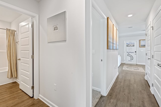 corridor featuring recessed lighting, wood finished floors, and baseboards