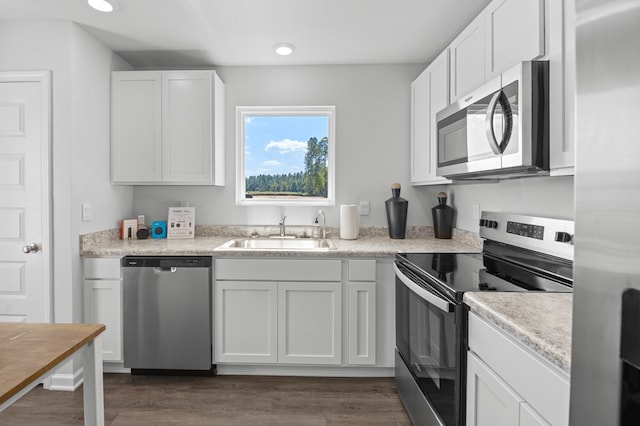 kitchen featuring stainless steel appliances, dark wood-type flooring, a sink, and white cabinetry