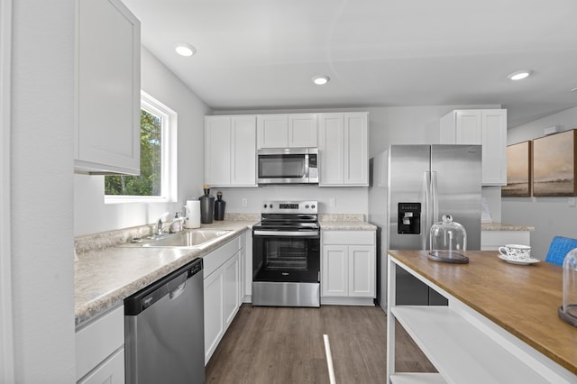 kitchen with appliances with stainless steel finishes, white cabinetry, and a sink