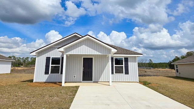 view of front of property with roof with shingles, board and batten siding, and a front yard