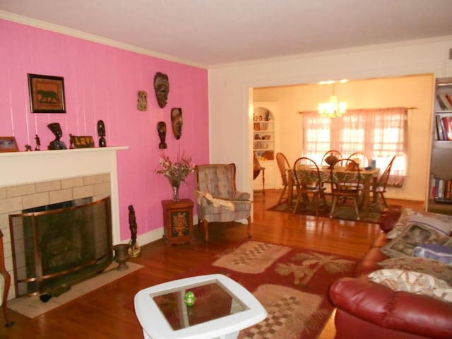 living area with a chandelier, dark wood-type flooring, a tile fireplace, and crown molding