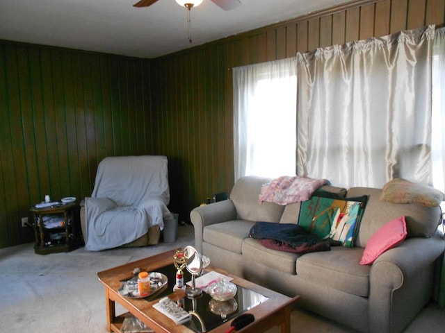 living room with a ceiling fan, carpet flooring, and wood walls