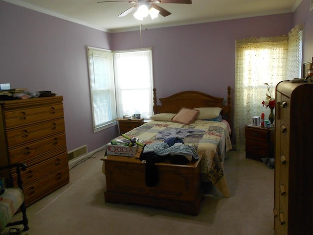 bedroom featuring light colored carpet, crown molding, visible vents, and ceiling fan