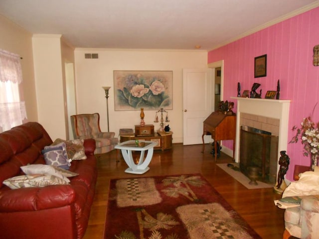 living area with a tile fireplace, visible vents, dark wood-style flooring, and ornamental molding