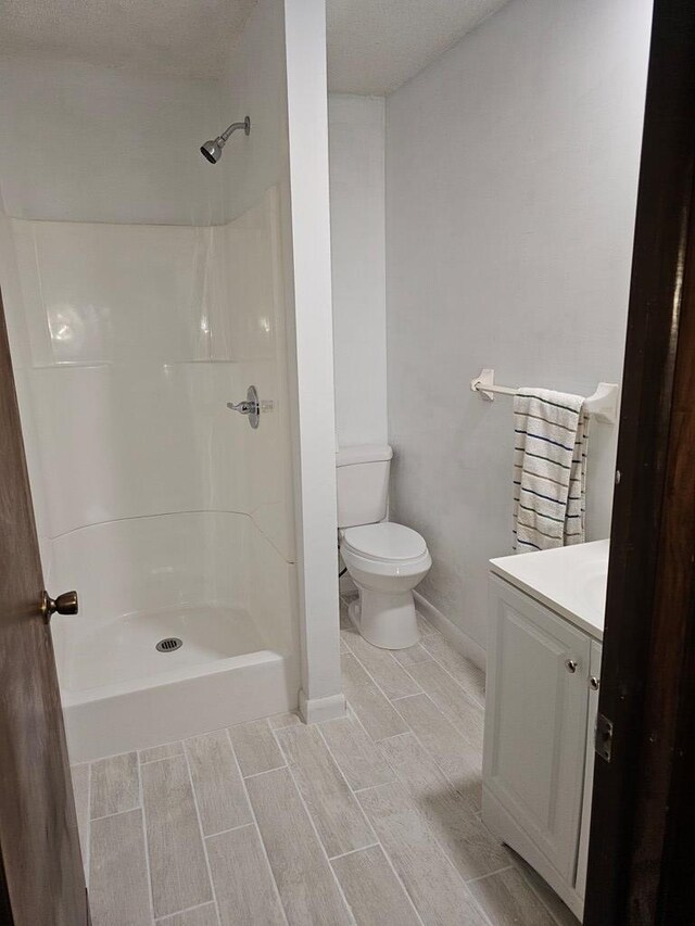 full bathroom with wood finish floors, toilet, a shower, and vanity