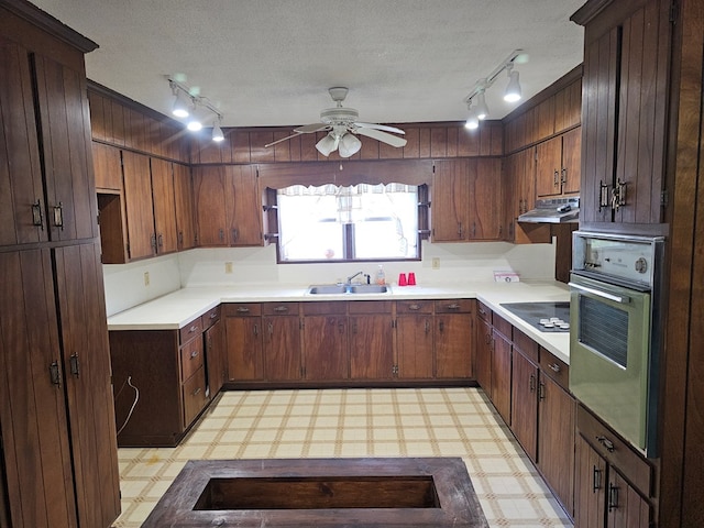 kitchen with light floors, rail lighting, wall oven, ceiling fan, and a sink