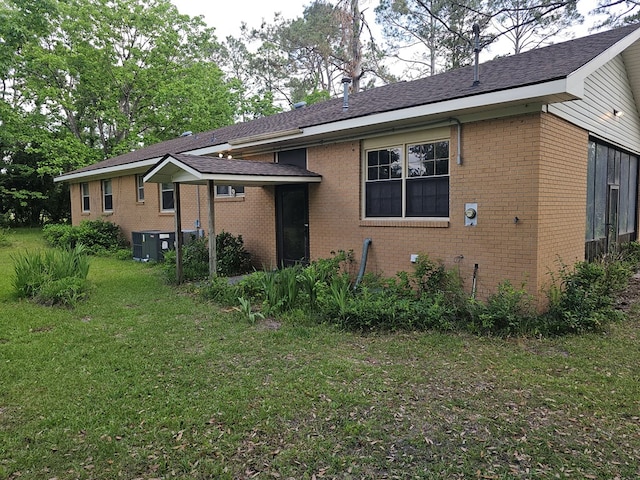 rear view of property featuring brick siding and a lawn