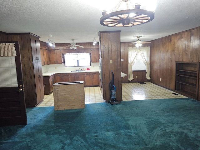 kitchen featuring a wealth of natural light, wood walls, ceiling fan with notable chandelier, and light countertops