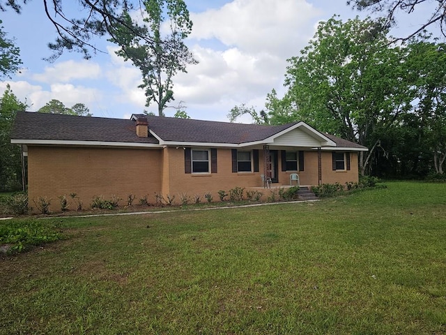 single story home with a porch, a chimney, a front yard, and brick siding