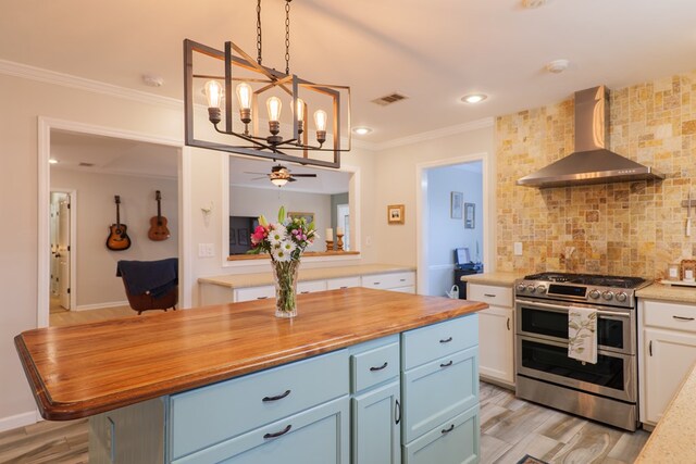 kitchen featuring range with two ovens, crown molding, wall chimney range hood, a notable chandelier, and backsplash