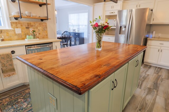 kitchen with stainless steel fridge, open shelves, wood counters, and green cabinetry