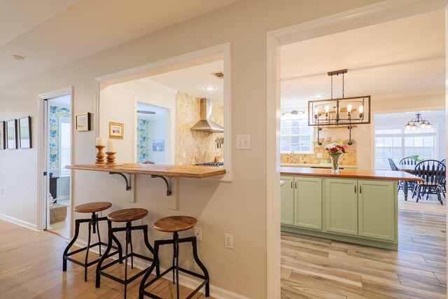 bar with plenty of natural light, light wood-style flooring, decorative backsplash, and exhaust hood