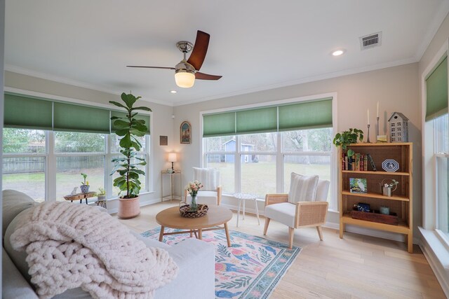 living room featuring visible vents, ornamental molding, a ceiling fan, and light wood finished floors