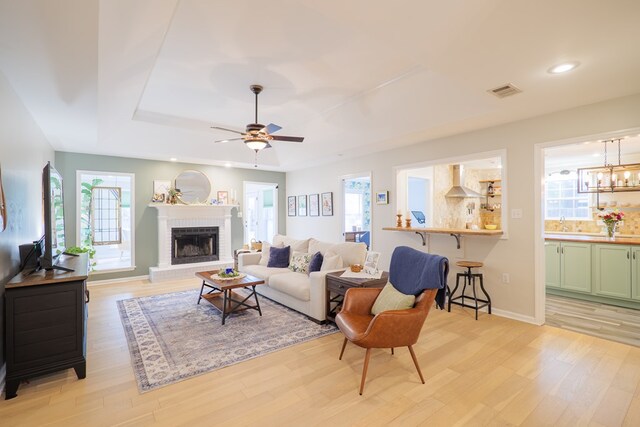 living area featuring a tray ceiling, plenty of natural light, and light wood-type flooring