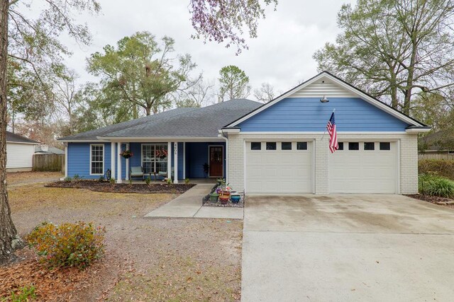 ranch-style home with a garage, brick siding, a porch, and concrete driveway