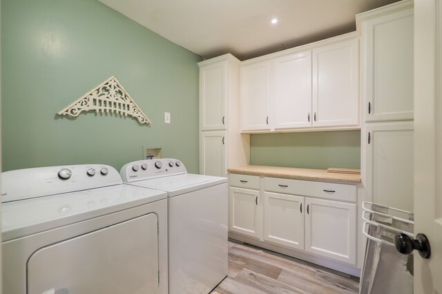clothes washing area featuring cabinet space, light wood-style flooring, and washing machine and clothes dryer