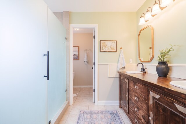 full bathroom with tile patterned flooring, double vanity, baseboards, and a sink