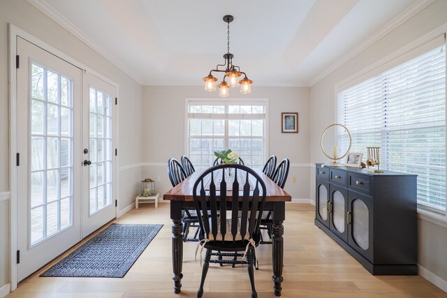 dining space with a chandelier, light wood-style flooring, french doors, and a healthy amount of sunlight
