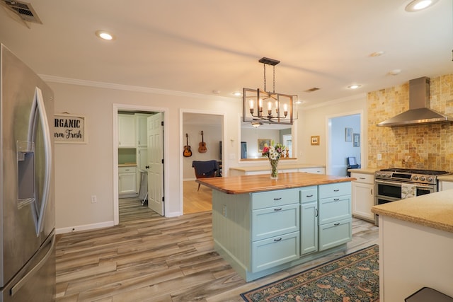 kitchen with butcher block counters, ornamental molding, decorative backsplash, stainless steel appliances, and wall chimney exhaust hood