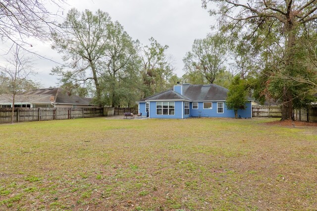 rear view of house featuring a yard and a fenced backyard