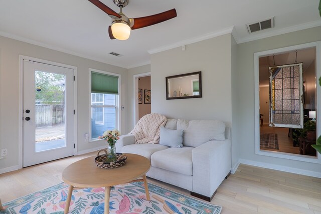 living area with visible vents, baseboards, ornamental molding, and light wood finished floors
