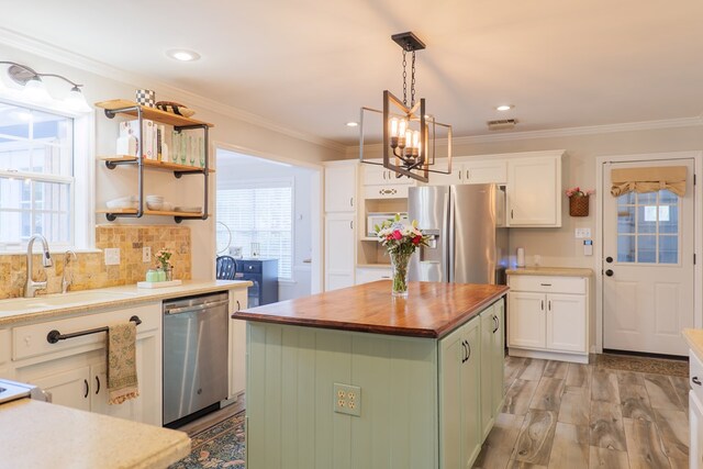 kitchen with a sink, white cabinetry, appliances with stainless steel finishes, an inviting chandelier, and wooden counters