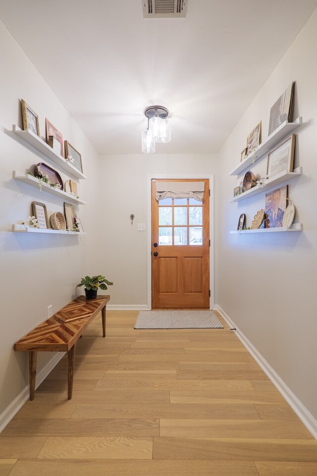 doorway to outside featuring visible vents, baseboards, and light wood finished floors