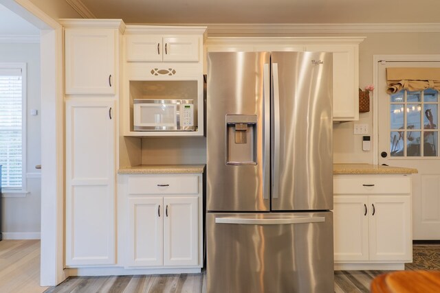 kitchen featuring white microwave, light stone countertops, ornamental molding, stainless steel refrigerator with ice dispenser, and white cabinetry