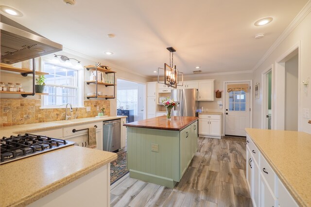kitchen with a sink, stainless steel appliances, extractor fan, white cabinets, and wood counters