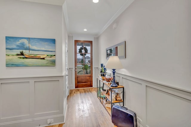 entryway with a wainscoted wall, crown molding, light wood-type flooring, a decorative wall, and recessed lighting